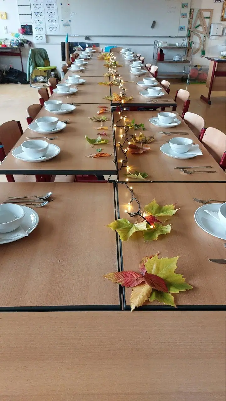 Ein lang gedeckter Tisch mit Lichterkette und herbstlicher Deko.
